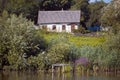 Shabby and worn old country house ruining lonely, abandoned home and yard on bank of countryside lake