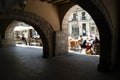 From the shade of a medieval arcaded pavement, a view to a busy, vibrant street in the old Catalan city of Girona, Spain. Bulky