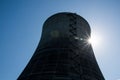Nuclear cooling tower under a blue sky with a sunburst