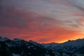 Shades of orange and pink clouds explode over the snow-capped Alps in this epic mountain sunset Royalty Free Stock Photo