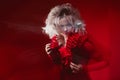 Shades of red. Portrait of Bizar attractive woman, with fashion make-up, in fantasy outfit, posing on a red background.