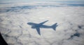 A shadow of an airplane is cast on a dense layer of white clouds below, creating a Royalty Free Stock Photo