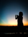 Shadow of Asian woman in Thailand standing to take photos of evening sunlight with smartphone, silhouette concept Royalty Free Stock Photo