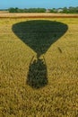 The shadow of a balloon flying over cultivated fields with a view of the cloudless sky Royalty Free Stock Photo