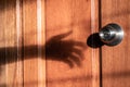 Shadow of burglar`s hand trying to open the door Royalty Free Stock Photo