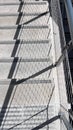 Chain link fence casting shadow over stairs