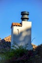 Shadow chimney with metal vents and red adobe roof tiles in downtown neighborhood in city with blue sky Royalty Free Stock Photo