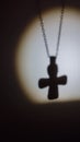 the shadow of a Christian cross on a chain in the light of a lantern