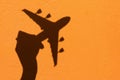 Shadow of Hand holding airplane model on Orange wall background Royalty Free Stock Photo