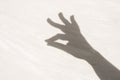 shadow of a hand with two fingers clasped on a light textured surface. Royalty Free Stock Photo