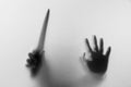 Shadow hands with knife of the Man behind frosted glass. Blurry h Royalty Free Stock Photo