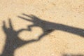 Shadow hands making heart icon on sand at the beach Royalty Free Stock Photo