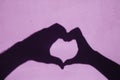 Shadow of Hands Making Heart Shape on pink background. Royalty Free Stock Photo