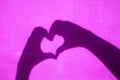 Shadow of Hands Making Heart Shape on pink background. Royalty Free Stock Photo