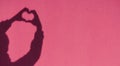 Shadow hands in the shape of a heart on the background of a colored sunny wall. Love, emotions, life, support concept