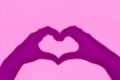 Shadow hands in the shape of heart on a pink background