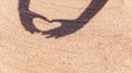 Shadow from hands in the shape of heart on the sand on beach with space for the text. Sea travel and holiday. Royalty Free Stock Photo