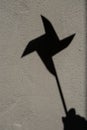 Shadow of holding pinwheel on cement wall, vertical picture Royalty Free Stock Photo