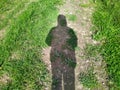 shadow of a hooded monk on the grass at daytime.