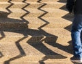 Shadow of a man climbing steps with a zig zag pattern of the hand rail