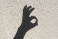 The shadow of a man`s hand on the wall shows an okay gesture Royalty Free Stock Photo