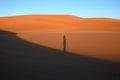 The shadow of the man standing on the sand dune in the desert. Royalty Free Stock Photo