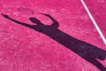 Shadow of mature man hitting tennis ball with racket on purple court Royalty Free Stock Photo