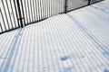 The shadow from a metal fence falls on clean snow, on a winter sunny day. Royalty Free Stock Photo