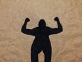 Shadow of muscle man on the beach, silhouette of strong man in the sand