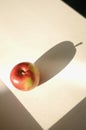 Shadow of one ripe apple on light background. Minimalistic food photography