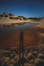 Shadow of a person cast on the lake surrounded by sand dunes and shrubs Royalty Free Stock Photo