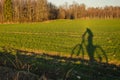 The shadow of a person riding a bicycle in a green field Royalty Free Stock Photo