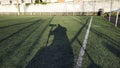 Shadow of a photographer with a telephoto lens sitting on an artificial grass soccer Royalty Free Stock Photo