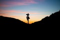 Shadow of a road sign on top of a mountain against a bright sunset sky