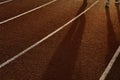 Shadow of running people for exercise on the red and white line track floor of sport field in the morning sunrise background Royalty Free Stock Photo