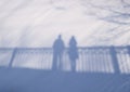 Shadow silhouette of couple man and woman standing on a bridge on snow background on sunny winter day Royalty Free Stock Photo