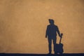 Shadow and silhouette of the musician in a hat with a guitar against the background of the concrete wall