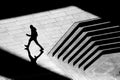 Shadow silhouette of teenage boy walking city street sidewalk, in black and white Royalty Free Stock Photo