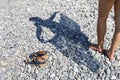 Shadow silhouette of woman with shawl in her hands on pebble beach and pair sandals