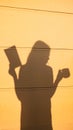 Shadow silhouette of a young woman reading book and drinking tea coffee in sunlight. Royalty Free Stock Photo