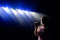 Shadow of singer in light. Portrait of beautiful singing woman on dark background Royalty Free Stock Photo