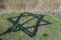 The shadow of six-pointed star of David. Monument to the victims of the Holocaust in the village of Bogdanovka. Ukraine.