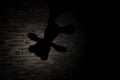 Shadow of a teddy bear hanging on a wall lit by a lantern in the dark Royalty Free Stock Photo