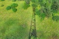 Shadow of telecommunication tower with radio antennas and satellite dishes on the green field with grass, bushes and Royalty Free Stock Photo