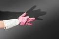 Shadow theater. Hands in rubber gloves shows the figure of a dog. On the dark wall is a shadow of hands in the shape of Royalty Free Stock Photo