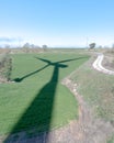 Shadow of a wind turbine cast on a green field and a winding road