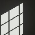 A shadow of a window grid is cast on a dark surface, creating a pattern of rectangula Royalty Free Stock Photo