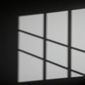 Shadow of a window with a grid pattern cast on a plain, light-colored wall. The Royalty Free Stock Photo