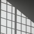 Shadow of a window with a grid pattern cast on a white wall. The shadow creates Royalty Free Stock Photo