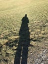 Shadow of a woman cast on frozen yellowish grass